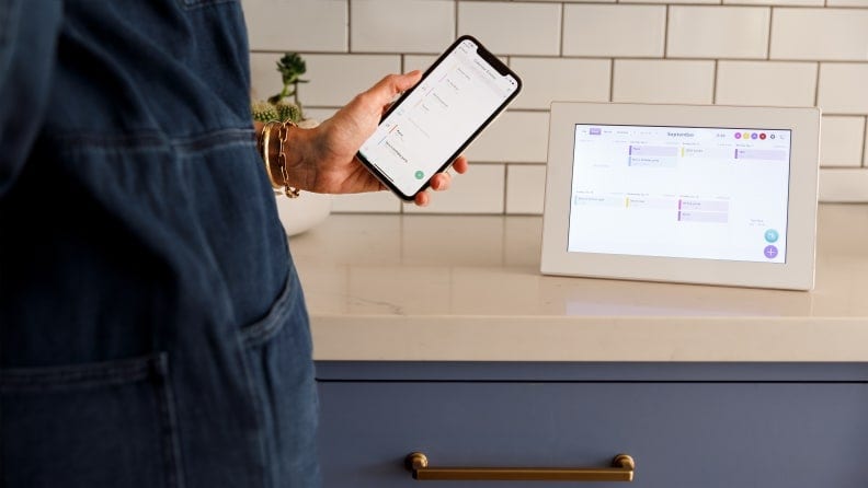 A person uses a mobile phone to use the Skylight Calendar app.