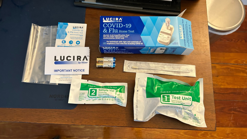 Contents of a COVID test kit including a cotton swab, batteries, and several pouches.