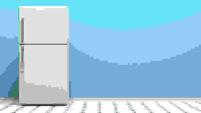 A top-freezer refrigerator sits in front of a blank aqua blue wall.