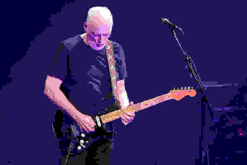 Photo of guitarist David Gilmour playing his famous Black Strat live on stage.