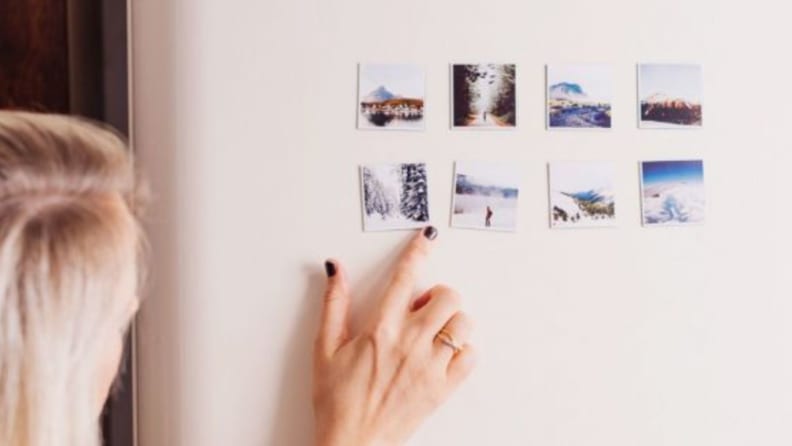 A woman points to photo magnets on a refriderator