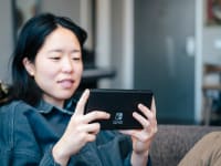 A person playing a nintendo switch oled on the couch