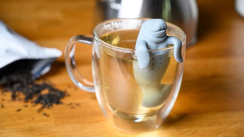 A glass teacup with a manatee infuser.