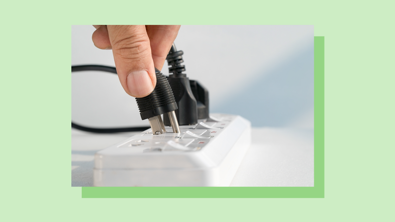 A person plugs an electrical cord into a surge protector.