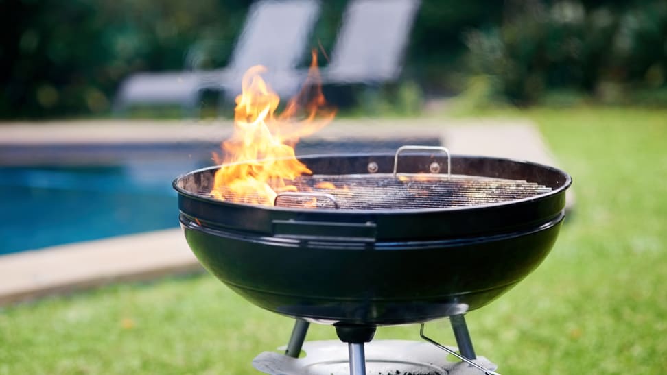 Charcoal grill with exposed flame in a backyard