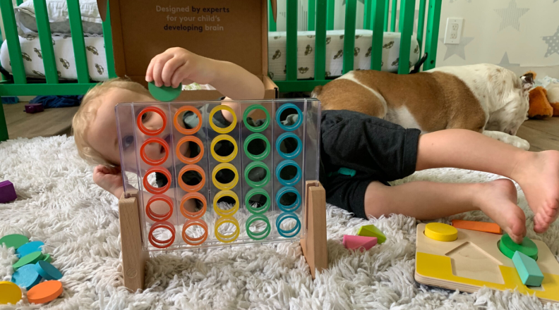 A child lays on the floor and plays with toys