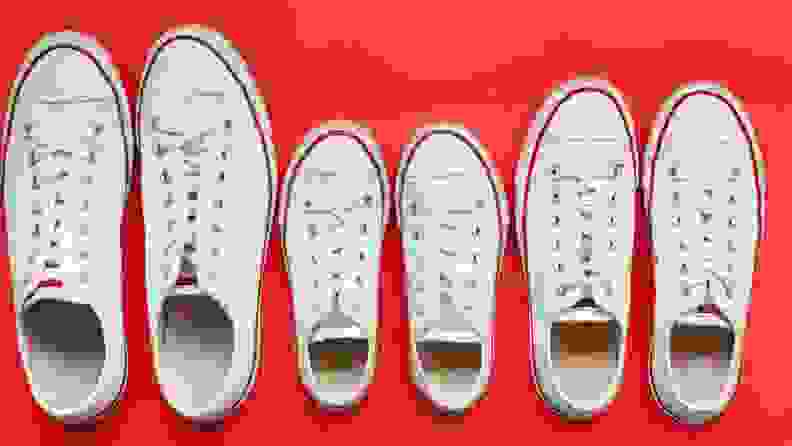 Three pairs of white sneakers on a red background