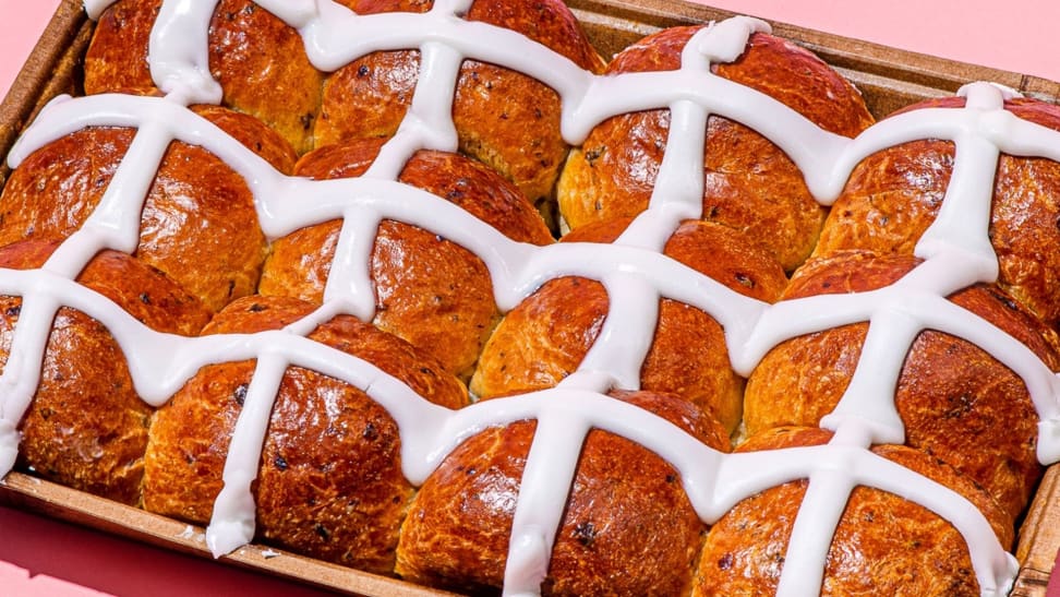 A close-up photo of hot cross buns, topped with the traditional white icing in a cross pattern.