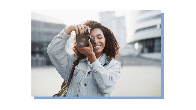 A photographer holds her camera to her face to snap a photo.