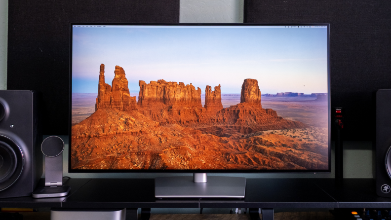 A large Dell Ultrasharp monitor showing a western landscape stands on a desk