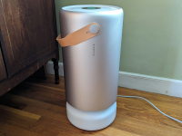 A silver Molekule air purifier is shown in a home on top of wooden floor.