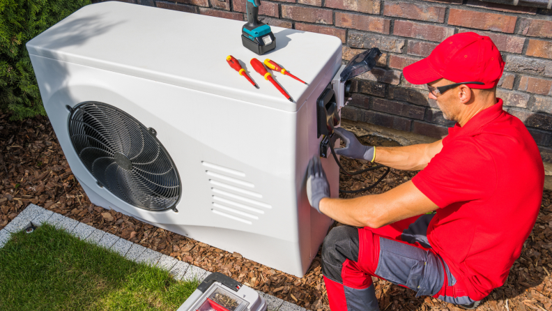 Technician installing heat pump outdoors.