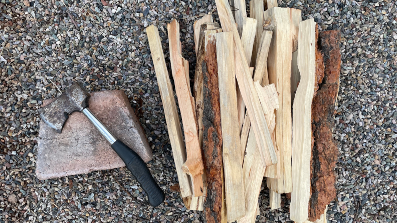 A stack of kindling and an axe on the ground.