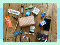 Small toiletry bag with assorted hygiene products scattered all around on tabletop surface.