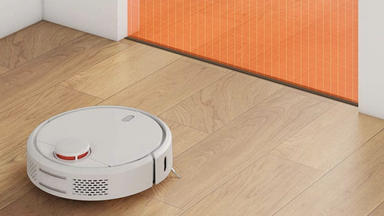 A robot vacuum on the floor close to a boundary marked by tape
