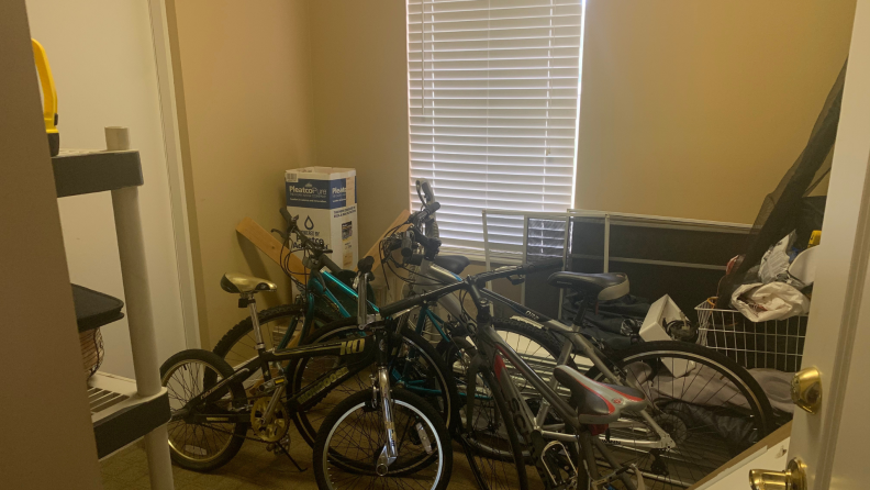 Safe room with bikes and hurricane shutters stored, along with a shelf of emergency supplies and other storage items