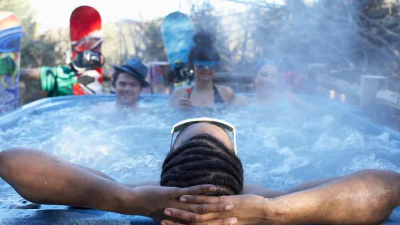 Snowboarders and skiers are relaxing in the hot tub after a day of skiing.
