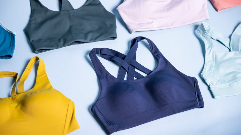 An array of sports bras in various colors on a pale blue background.