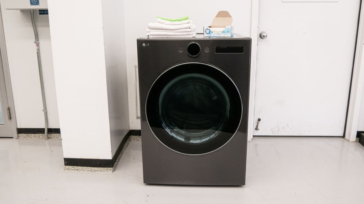 The dark steel-finished LG DLEX6700B dryer sits against a white wall next to a closed door in the Reviewed lab. Towels and a box of dyer sheets sit on the top of the machine.