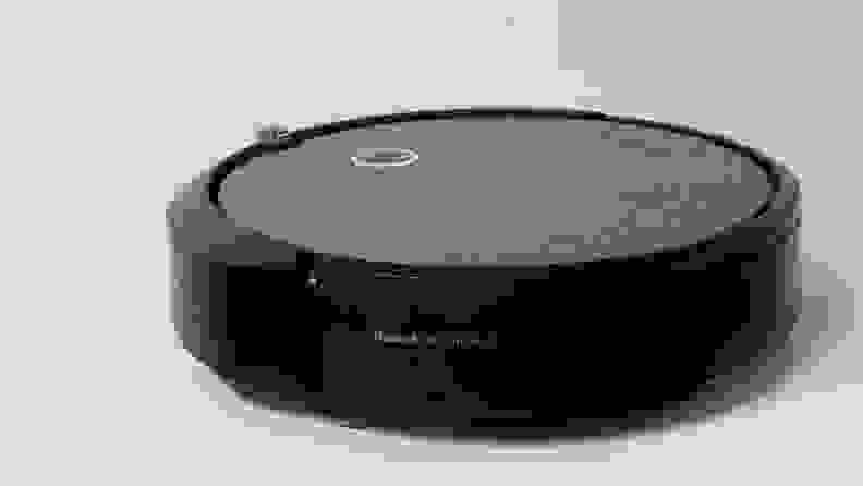 The iRobot Roomba i3 vacuum is circular, with a gray shell and a black bumper around it.