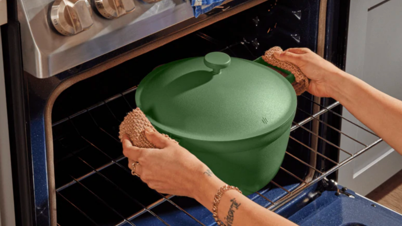 An image of a sage green Perfect Pot in someone's hands, being placed into an oven.