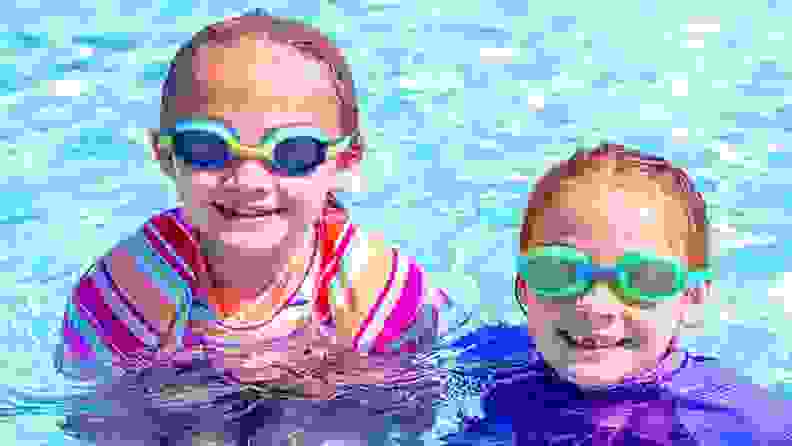 Two girls smile while wearing their swimming goggles