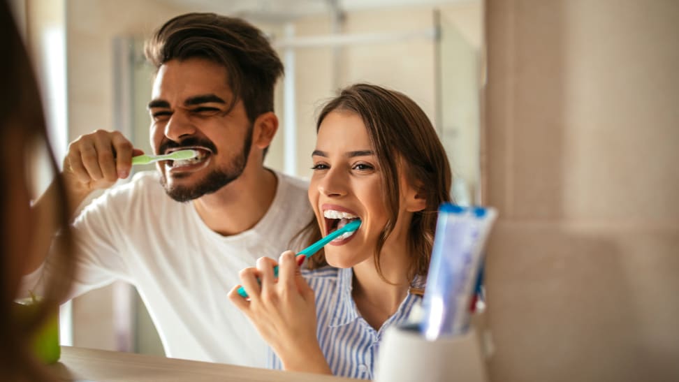 A photo of a man and woman brushing their teeth together.