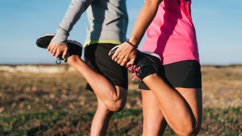 Sporty couple stretching legs outdoors before trail running workout outdoors. Fitness healthy lifestyle concept.