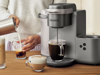 Photo of a model demonstrating a high-end Keurig single-serve coffee maker.