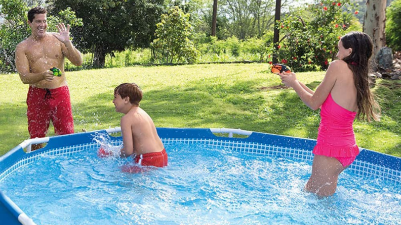 Family of three enjoying playing in pool outdoors together.