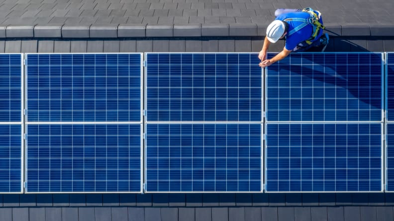 Person installing solar panels on roof.