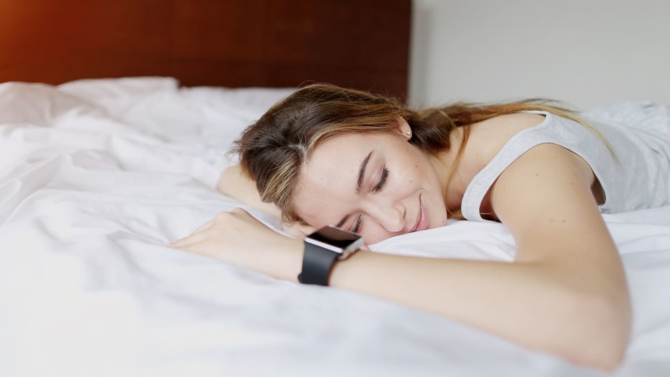 someone lies in bed with a sleep tracker on their wrist