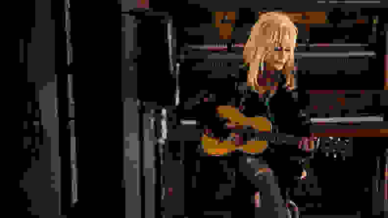 多莉·帕顿拿着吉他，如图所示