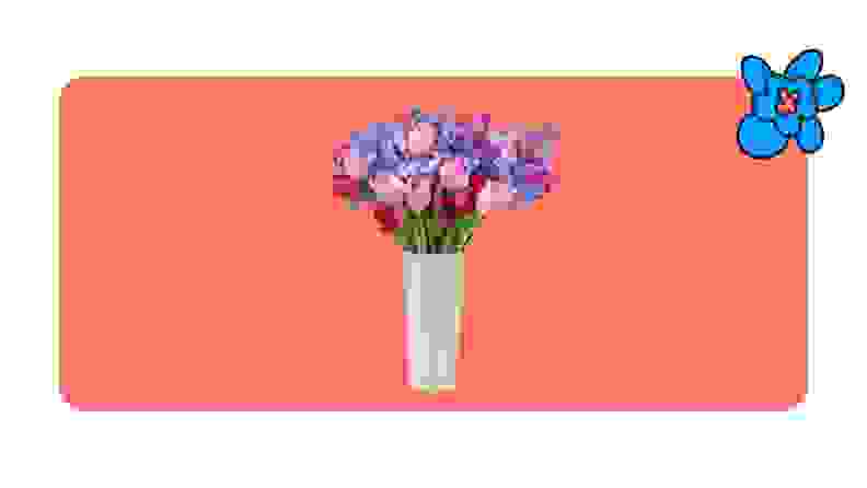 Mixed flower bouquet with purple and pink flowers in a white vase on a red background