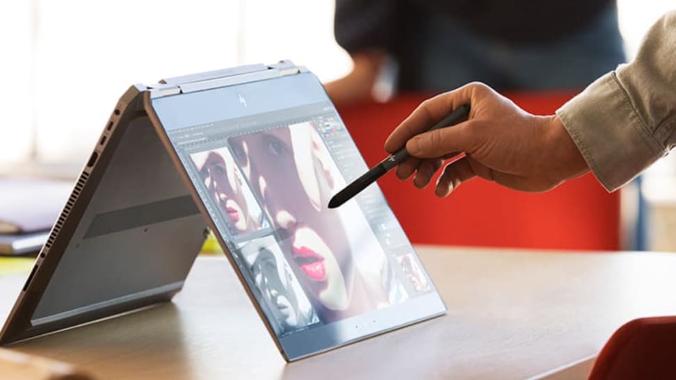 Man drawing on convertible laptop with stylus.