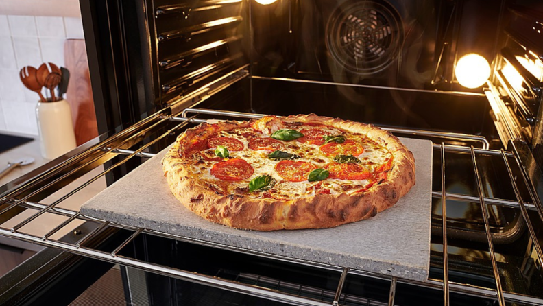 Bosch HBL8454UC oven door open with baked pizza on baking sheet on rack.