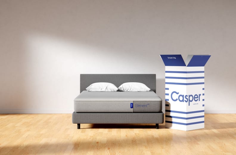 The Casper mattress set up in a complete bedding set with the Casper box next to it.