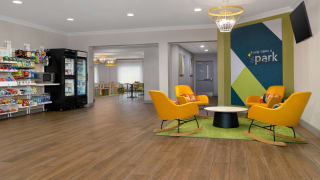 A modern Spark by Hilton lobby lounge with bright yellow chairs and a snack area, ideal for travelers booking last-minute hotel deals.