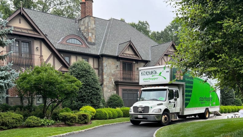 A moving truck in front of a brown historic home
