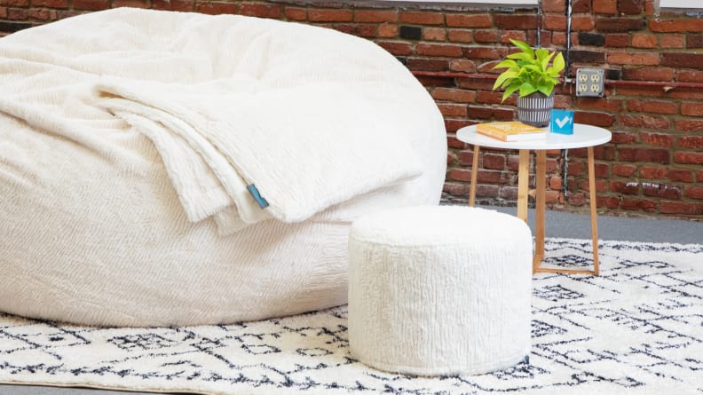 A squattoman sitting next to one of Lovesac’s Sacs.