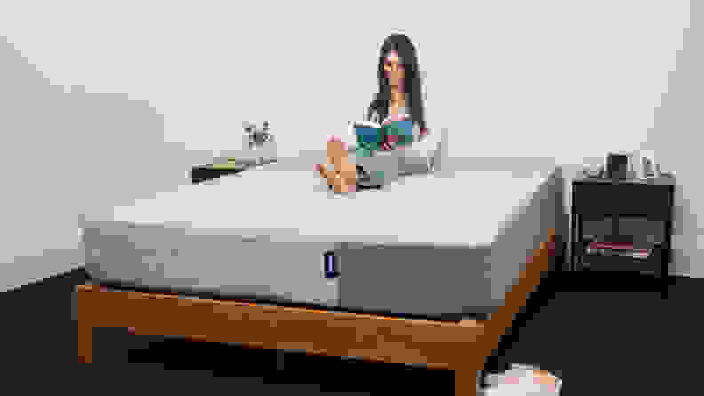 a woman sits on the Casper Original mattress and reads a book