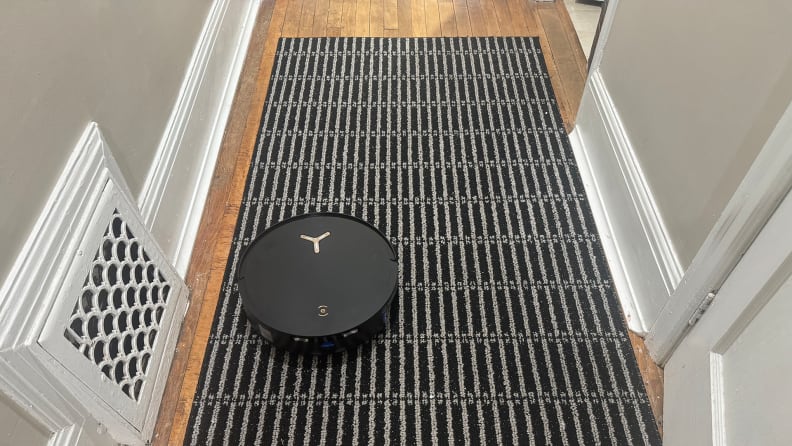 A black robot vacuum in a hallway