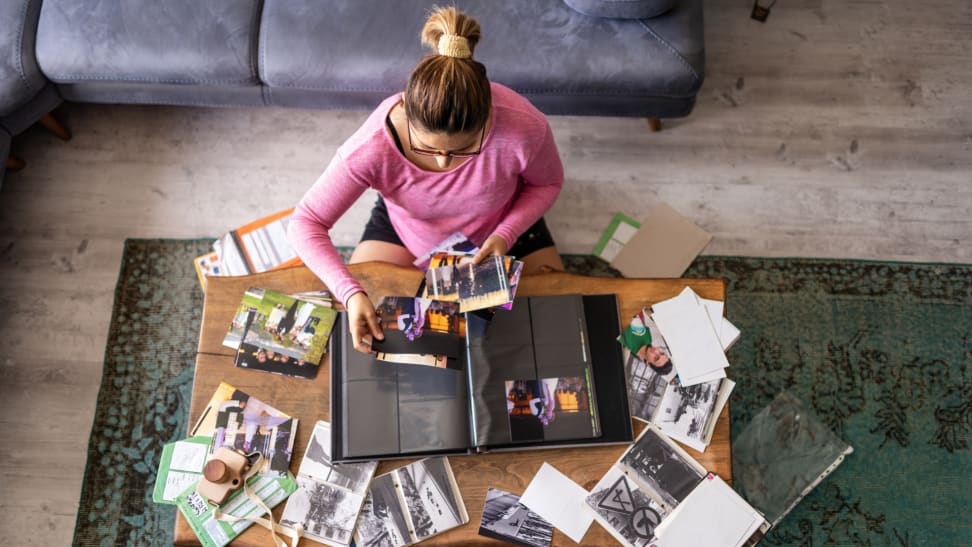 A person adds photos to a photo album at home.