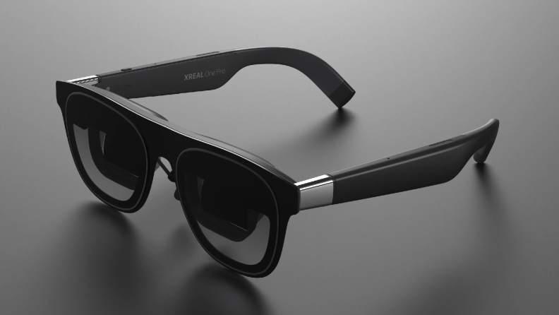 Sleek black XREAL One Pro smart glasses with a modern, polished design, featuring integrated technology for immersive experiences, displayed against a minimalist gray background.