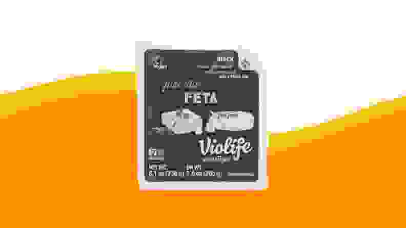 A product photo of Violife Feta on an orange and beige background.