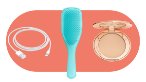 a charger cord, a blue hairbrush and a makeup compact sit on an orange oval graphic