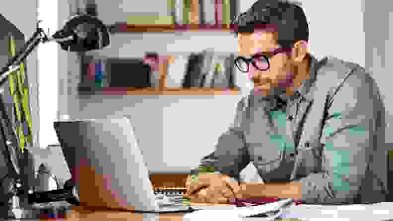 A person sits at a desk working on a laptop