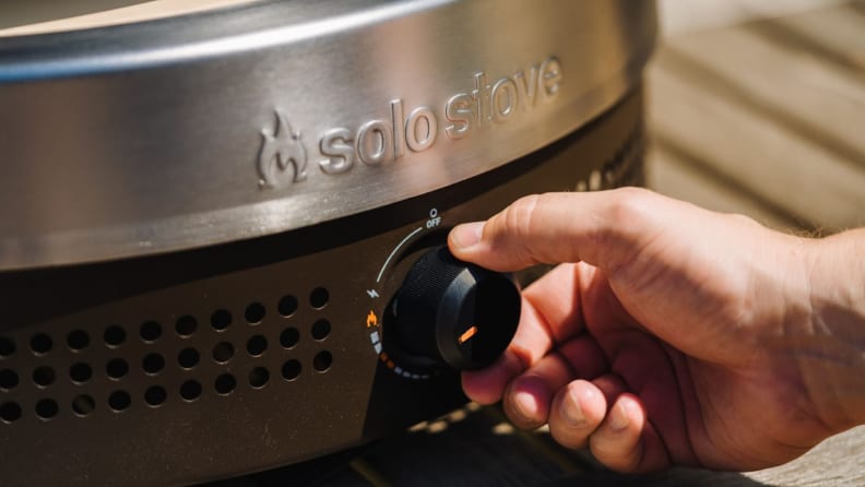 Hand adjusts temperature settings with knob on the Solo Pi Prime oven.