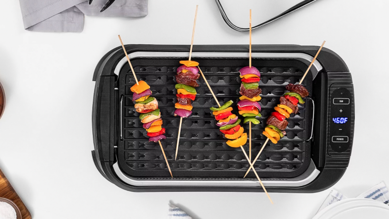 A no-smoke grill cooks five skewers.