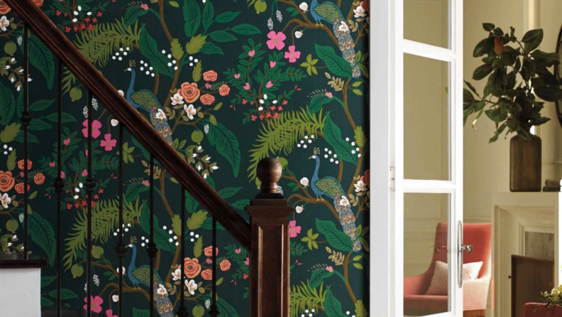 Dark emerald wallpaper with flowers and trees, next to wooden stairs and a set of doors